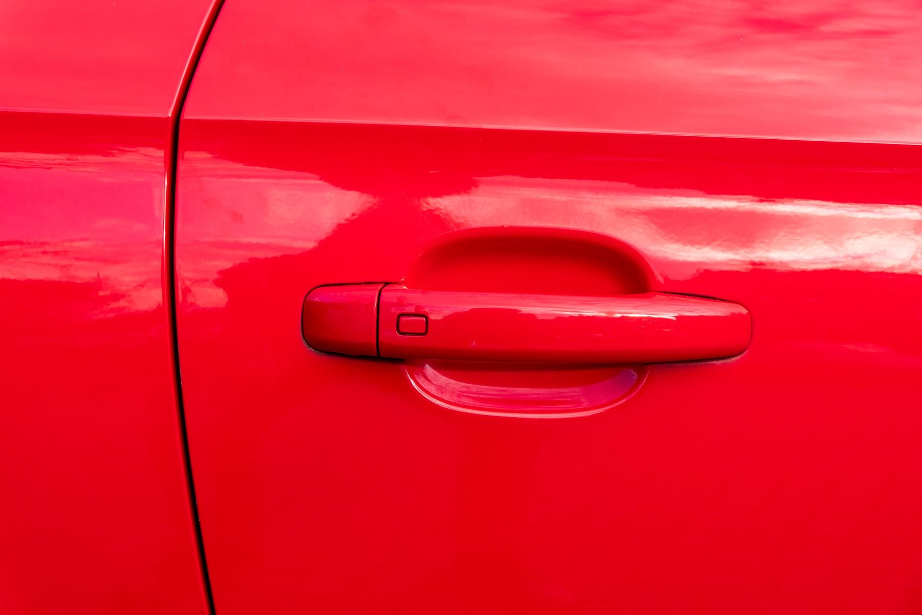 Detailed close-up of a bright red car door handle showcasing clean lines and vibrant color.